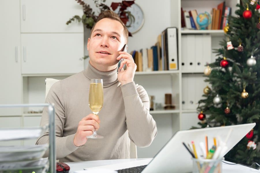man holding glass of champagne and having phone call during Christmas party