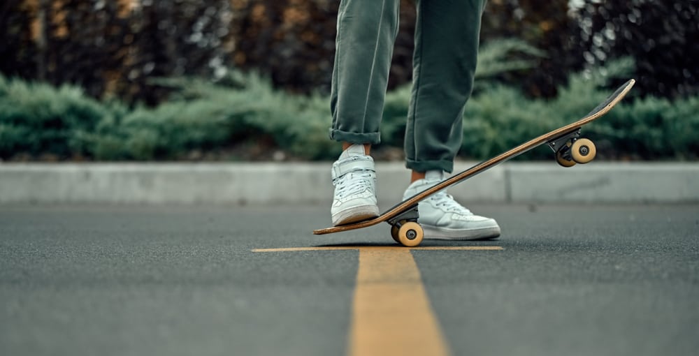 stylish man in white sneakers and green pants with a skateboard