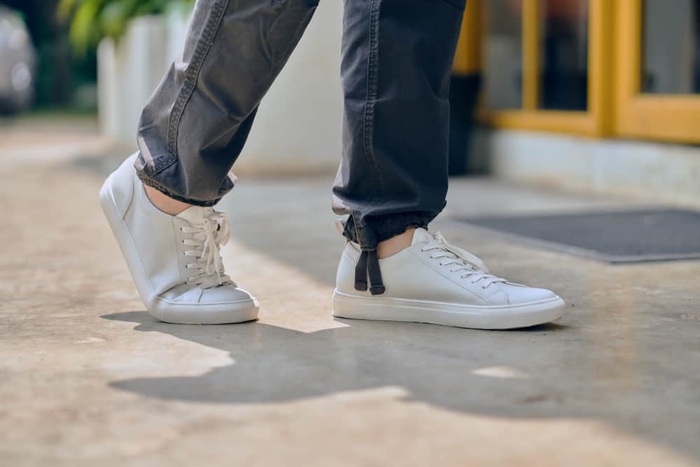 close up of man wearing white leather casual sneakers outdoor