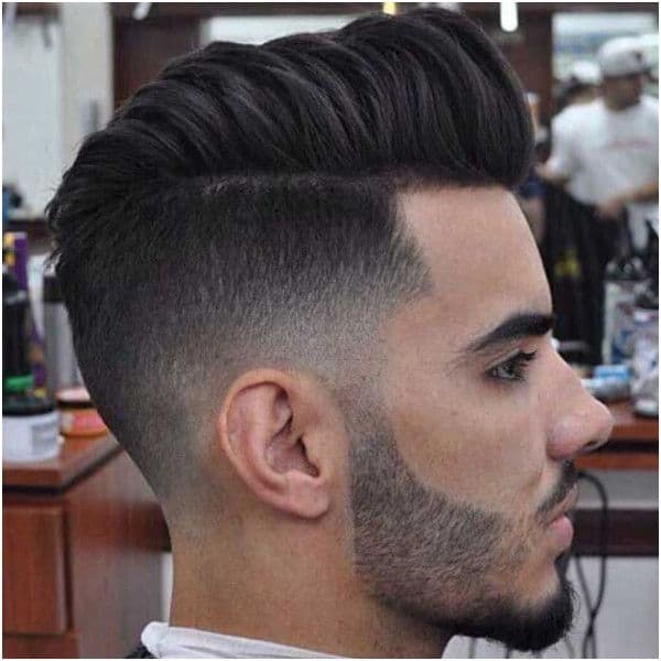 A haircut with extended hair on top and mid fade sides and back with faded hair connecting to the beard