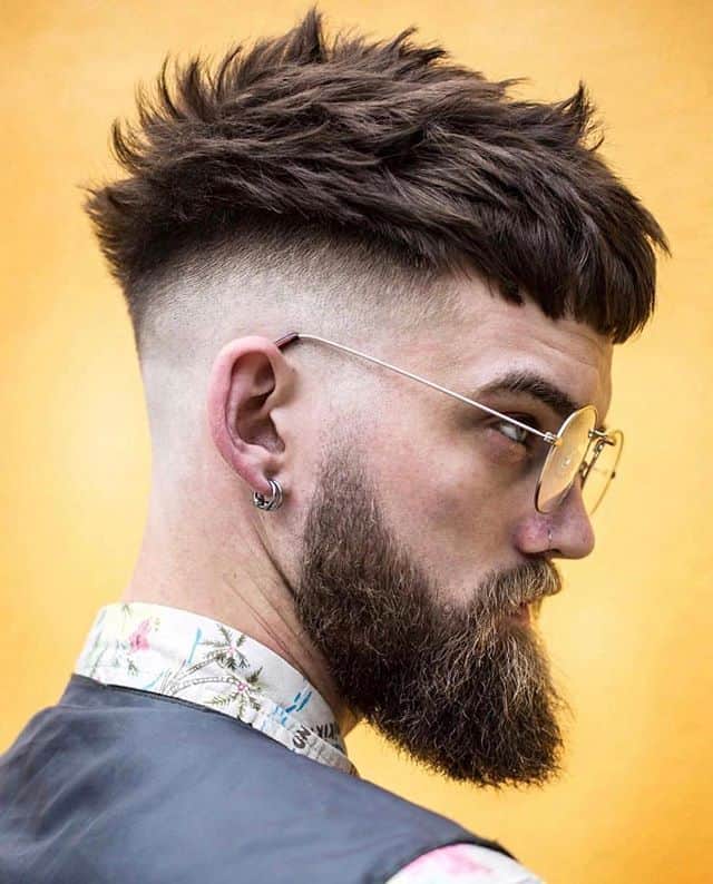 A haircut with thick side swept hair and mid-faded sides and back paired with beard